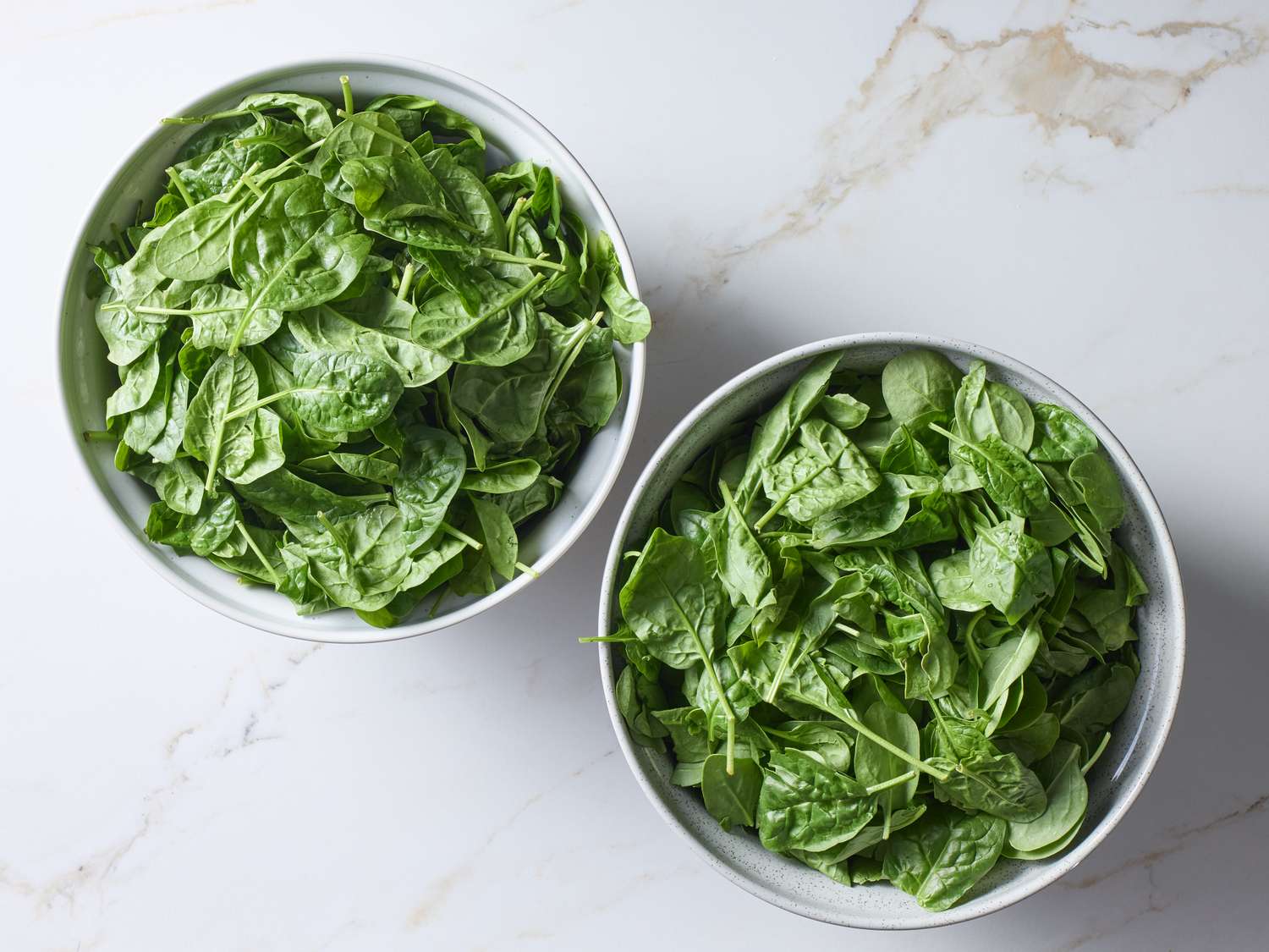 Two bowls of fresh spinach leaves