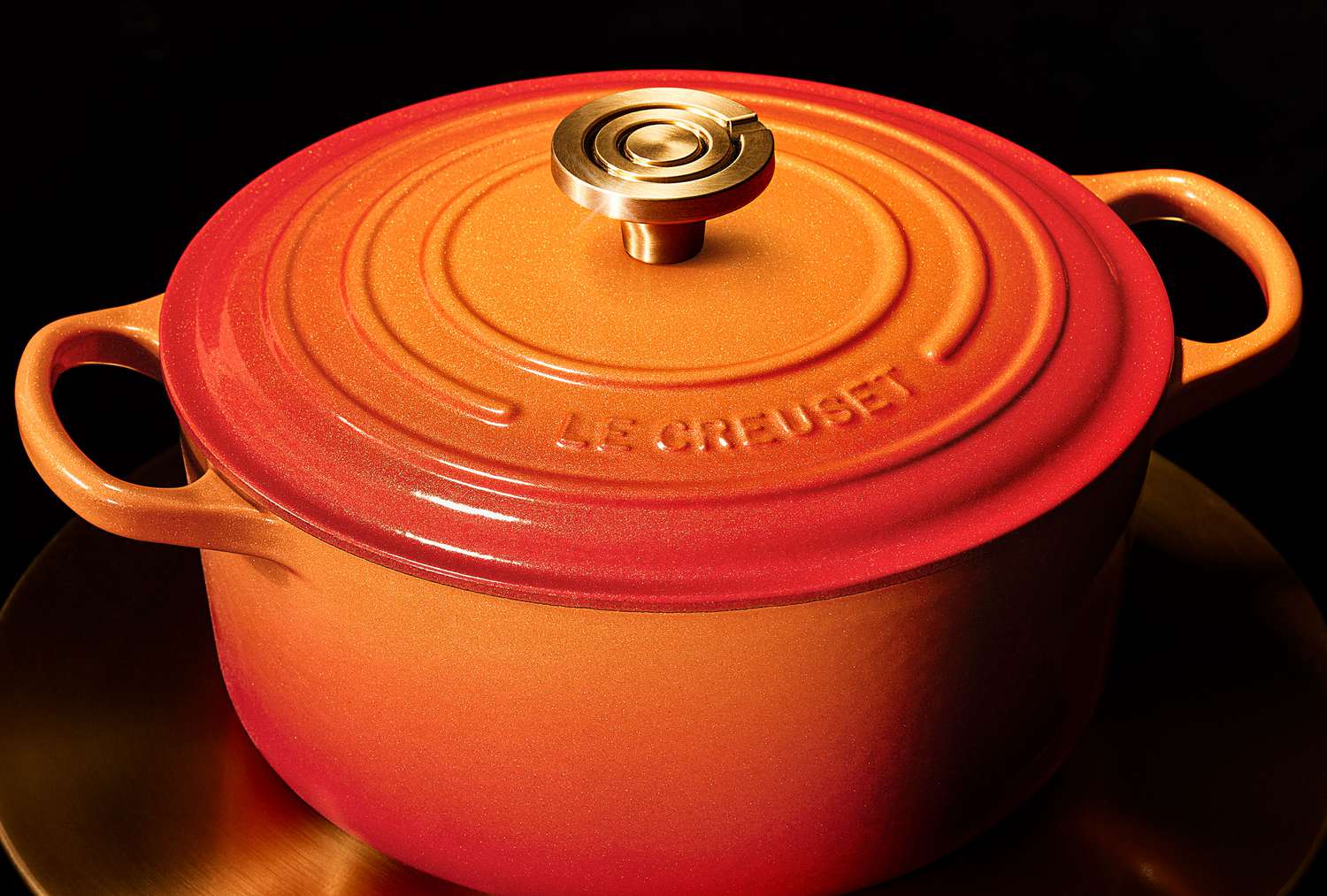 Le Creuset cast iron Dutch oven with lid and handles, brand logo engraved on top.