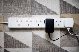 A power strip with plugs and adapters on a patterned rug