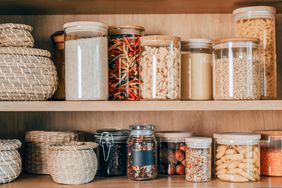 Pantry shelves with jars of food and wicker baskets organized storage
