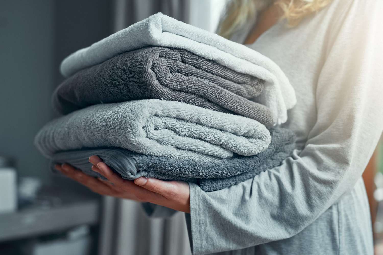 woman holding stack of folded towels