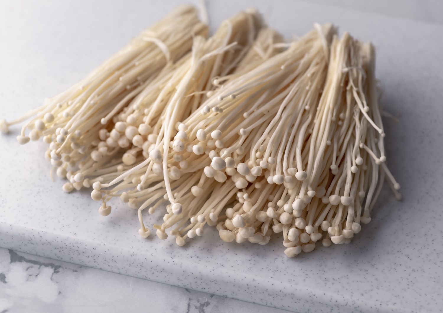 enoki mushrooms on cutting board