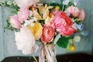 pink-and-white peony bouquet with blush ranunculus, yellow roses, and purple sweet peas