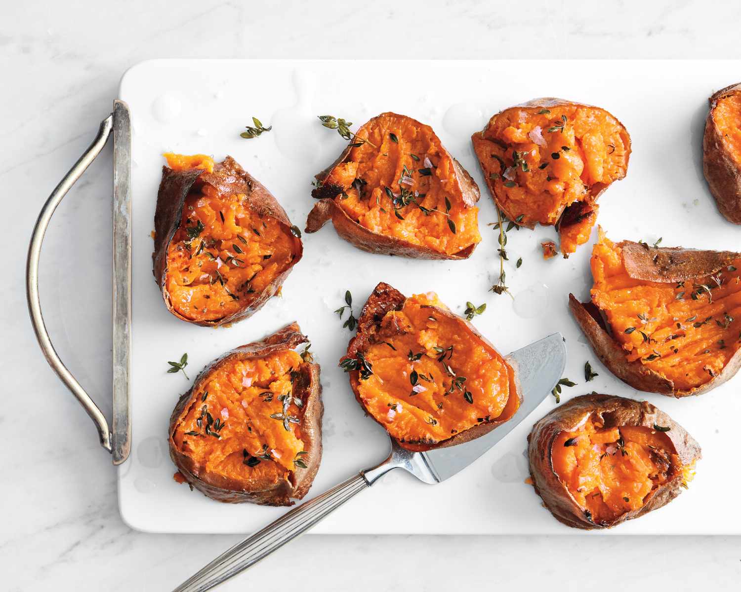 smashed sweet potato pieces with salt and thyme on white tray